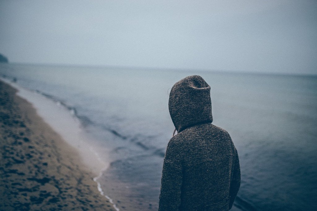 A figure in a hooded top walks along a coastal path.